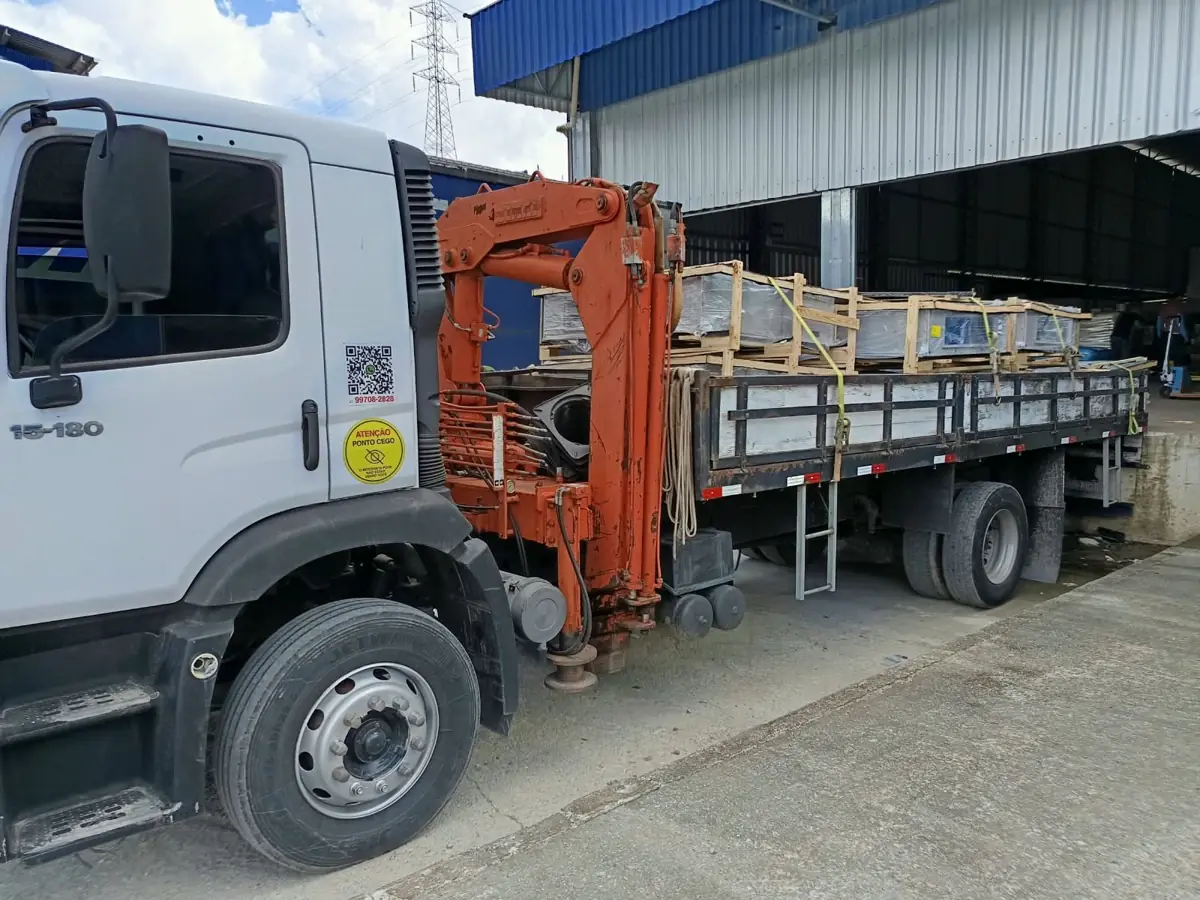 Caminhão munck carregado com caixas de equipamentos em doca de galpão