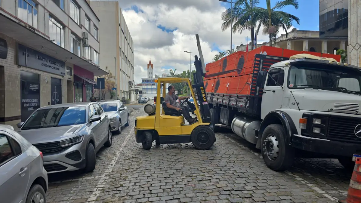 Empilhadeira descarregando caminhão em rua de paralelepípedo em Joinville