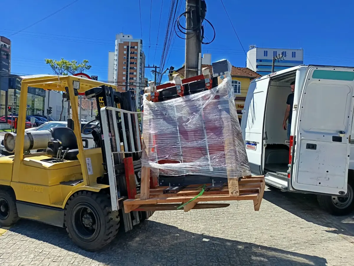 Empilhadeira do Xande movimentando equipamento embalado em palete até uma van em Joinville