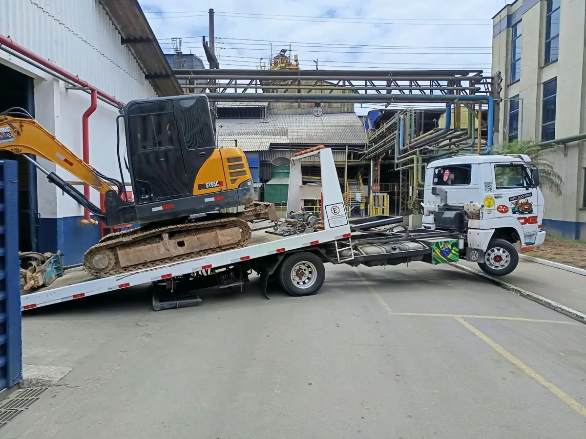 Miniescavadeira subindo na plataforma do guincho em área industrial de Joinville