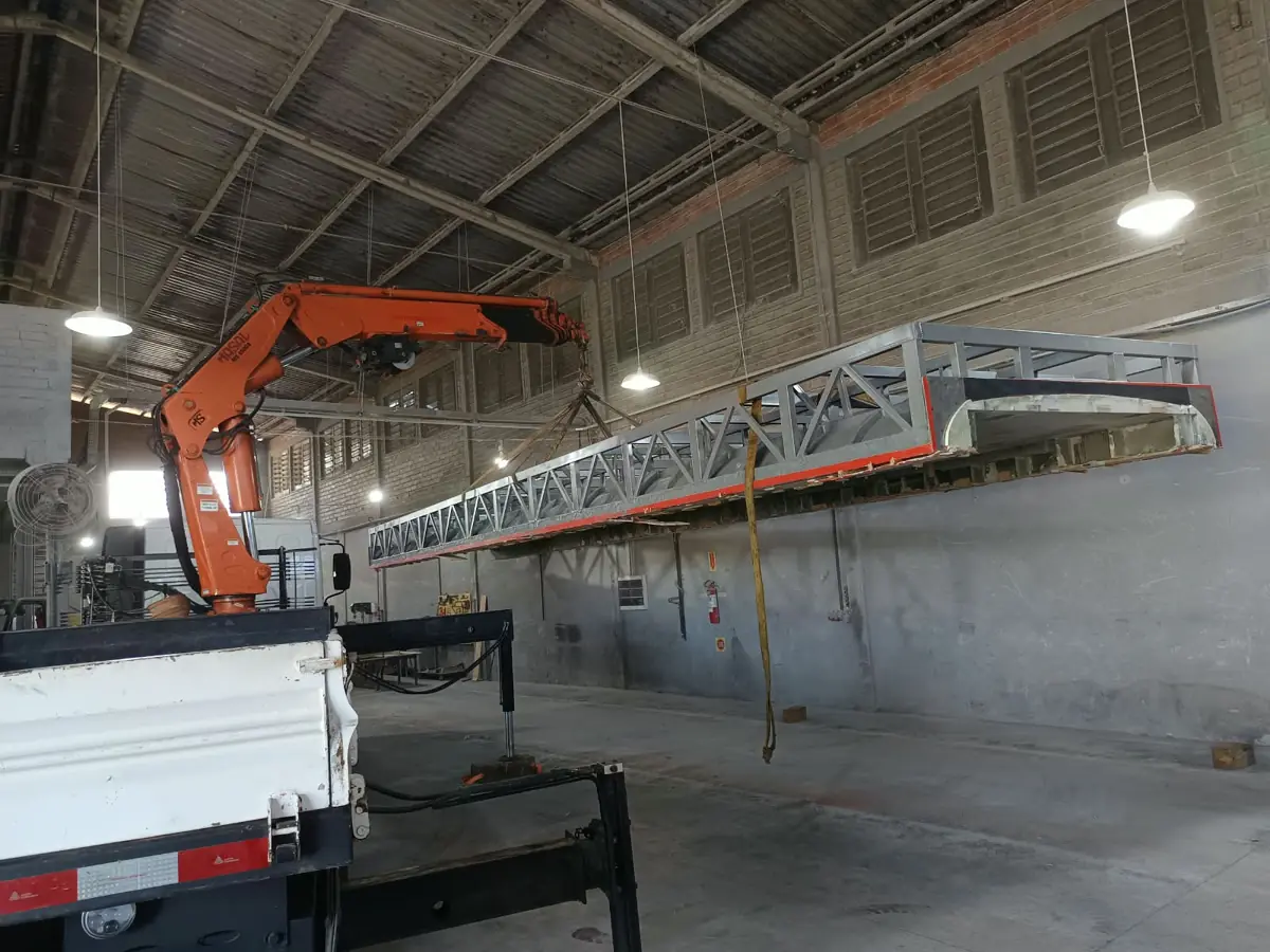 Munck içando estrutura metálica treliçada dentro de galpão