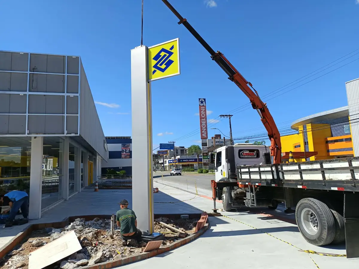 Munck instalando totem de agência bancária com equipe de montagem em Joinville