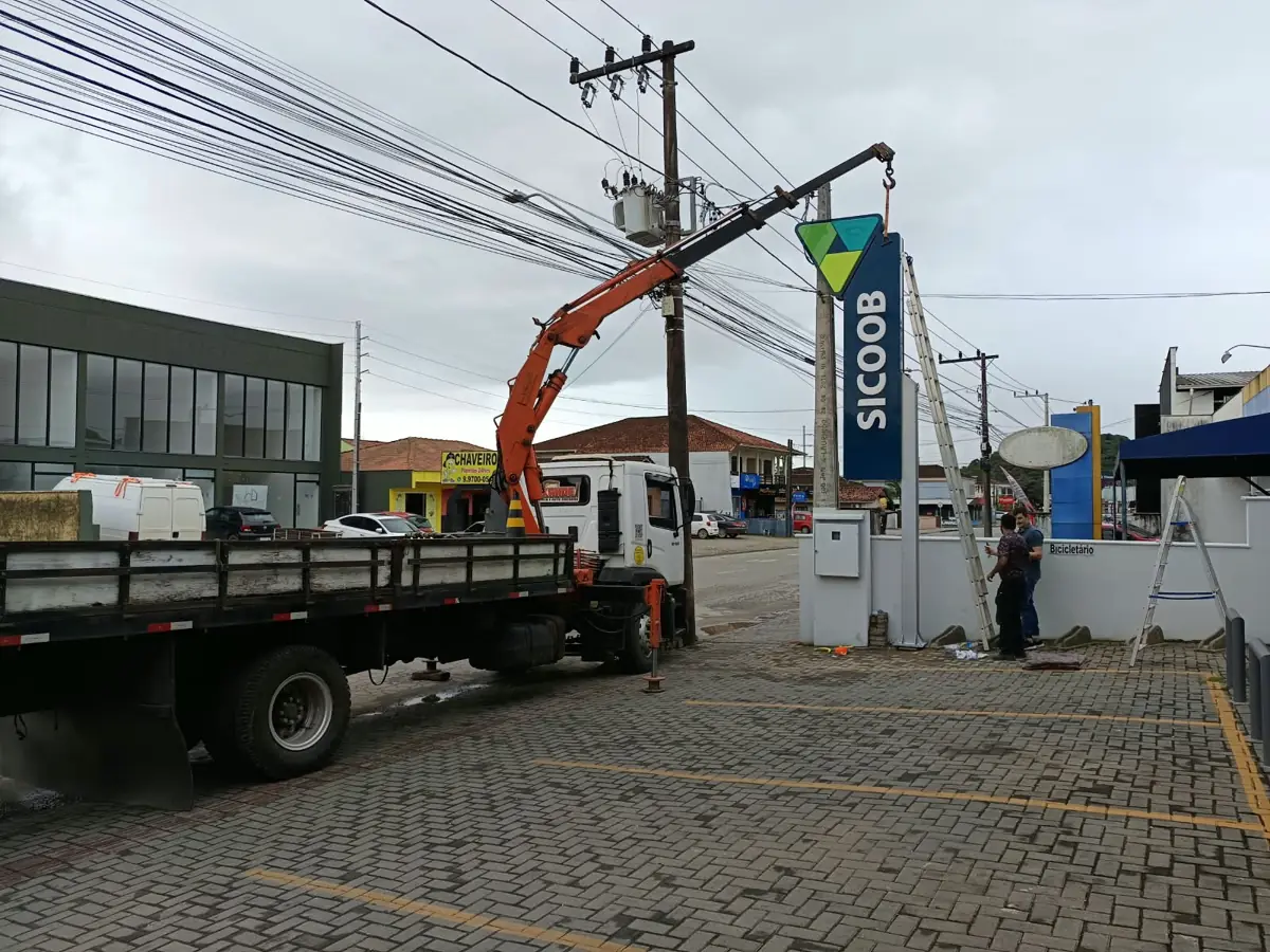 Munck posicionando totem luminoso entre a fiação elétrica em Joinville